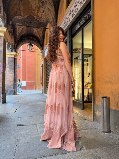 Abito lungo in tulle rosa cipria con stampa floreale e scollo incrociato sulla schiena.