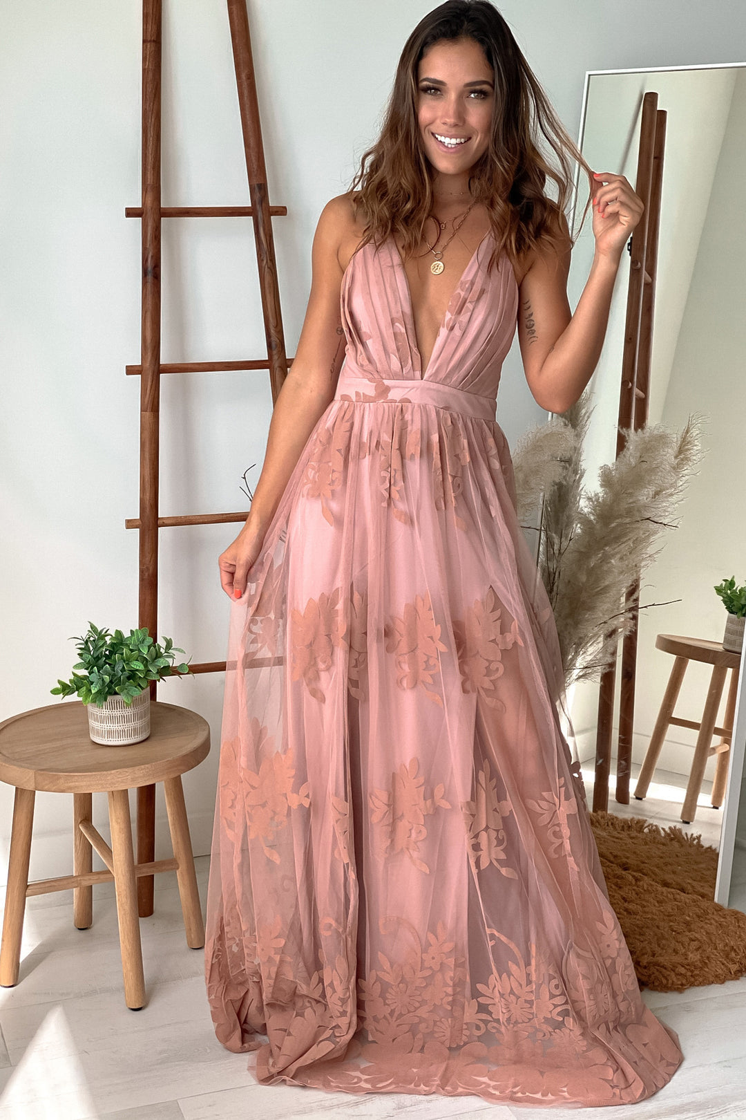 Abito lungo in tulle rosa cipria con stampa floreale e scollo incrociato sulla schiena.